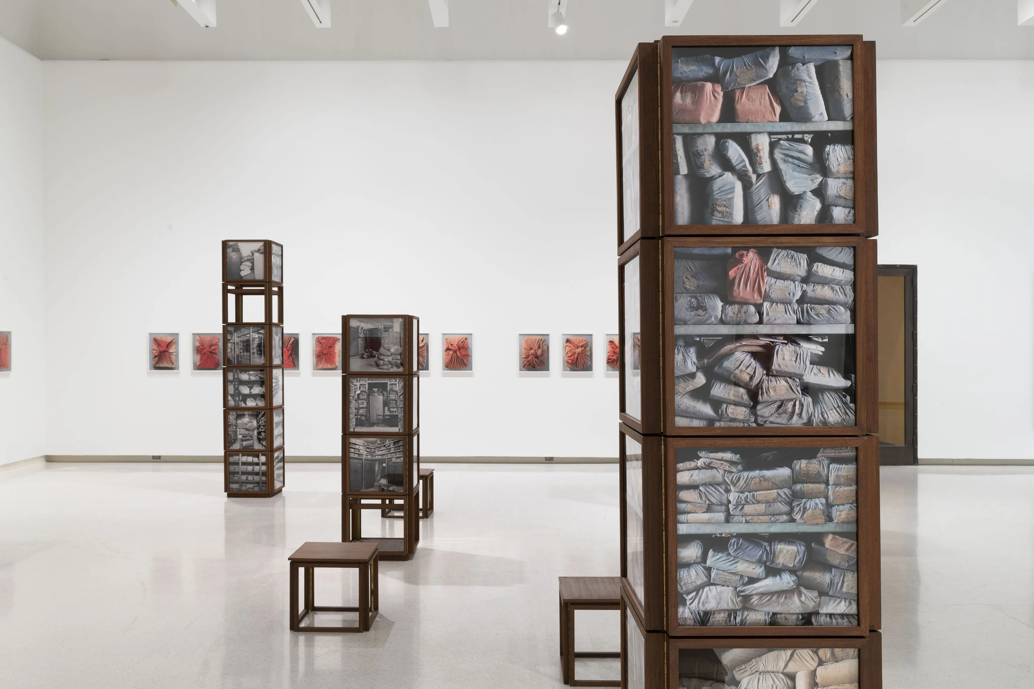 Three glass towers in a gallery filled with wrapped up parcels. 