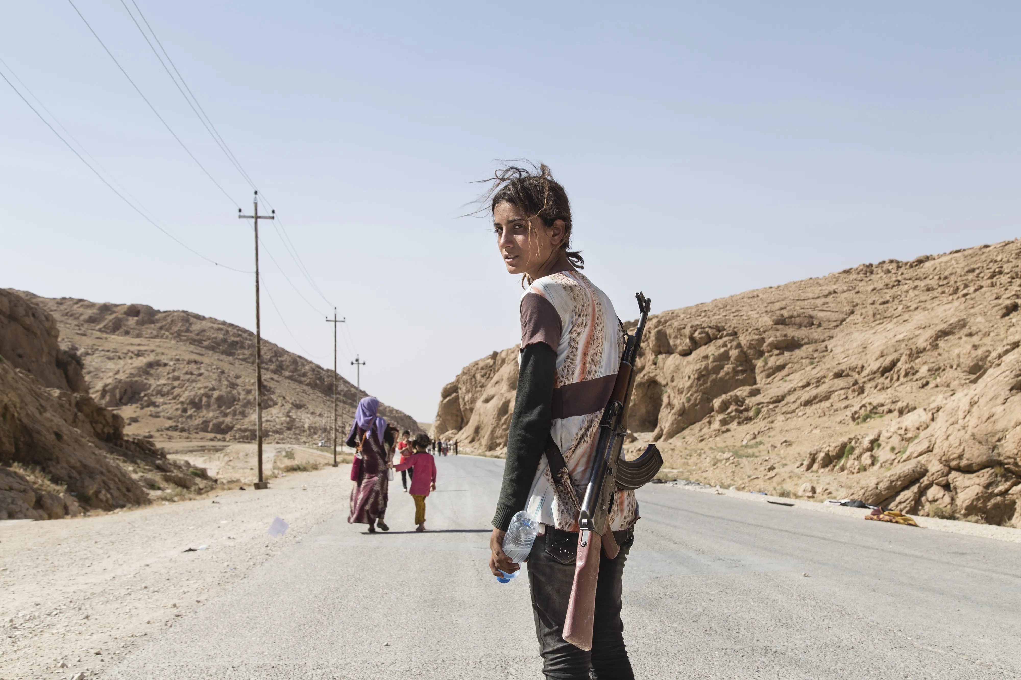 A person walking in the middle of the road with a gun.