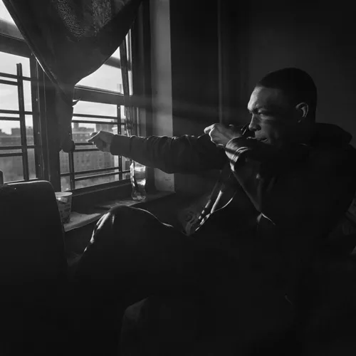 Black and white image of a man looking out a window